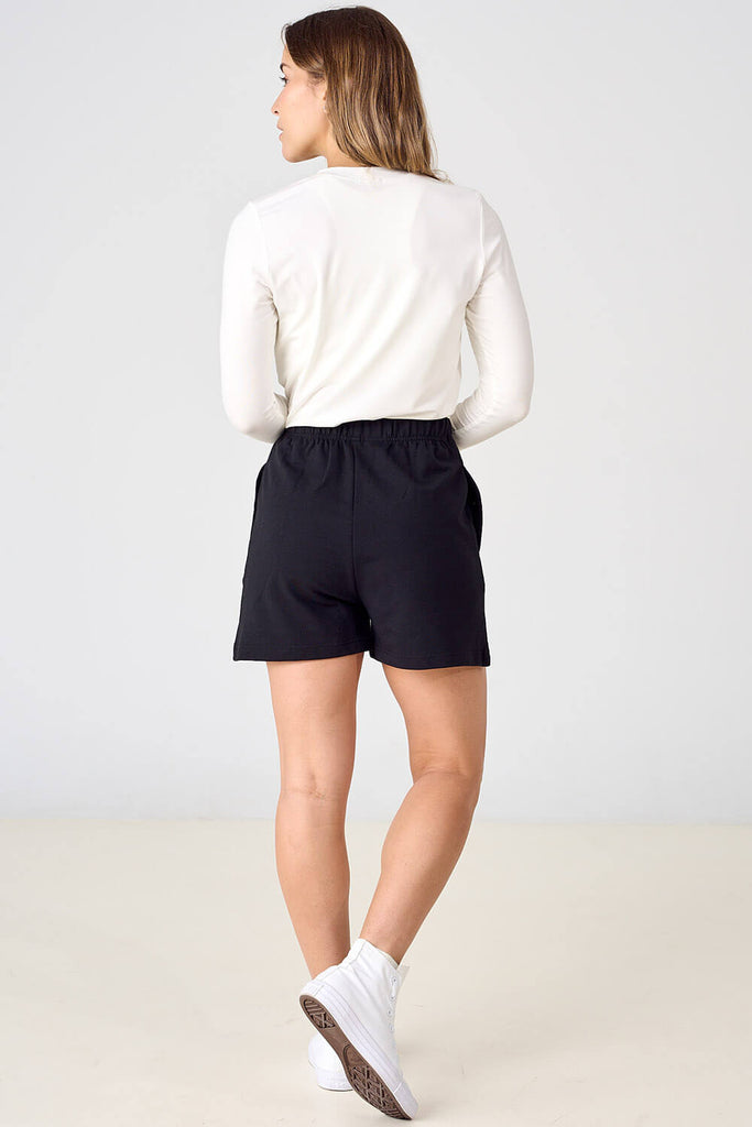 Woman wearing black tencel shorts with white long sleeve top. 