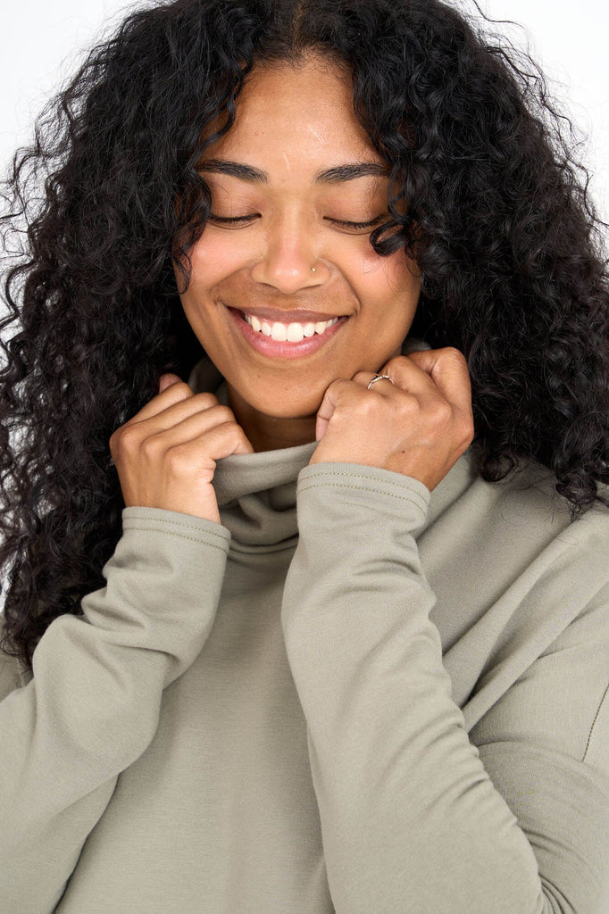 Close-up of woman wearing eucalyptus green Tencel oversized Abigail turtleneck, made by Canadian loungewear label Advika. 