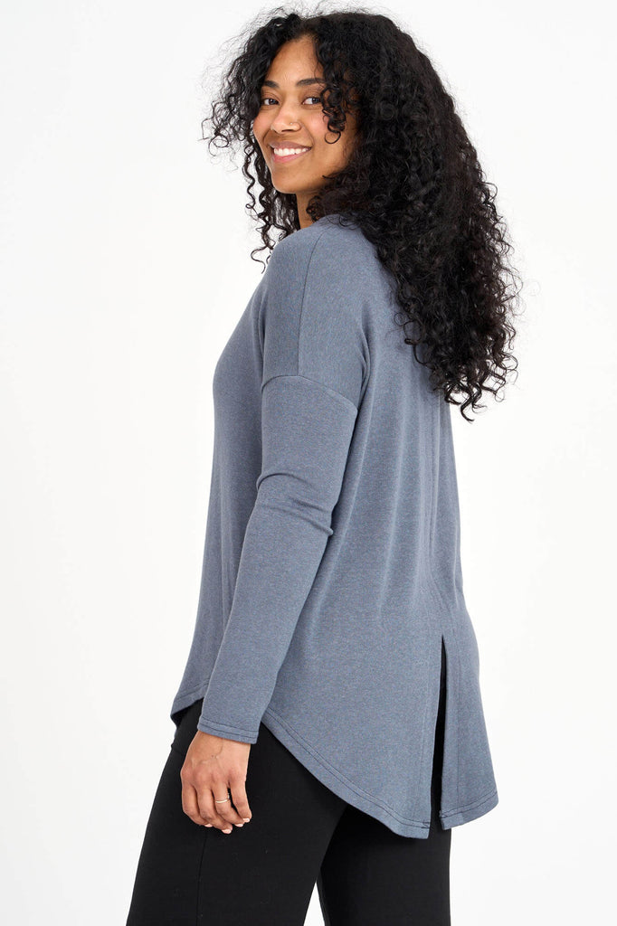 Side view of woman wearing a shadow grey Tencel scoopneck long sleeve top with split back hem, made by Canadian loungewear label Advika. 