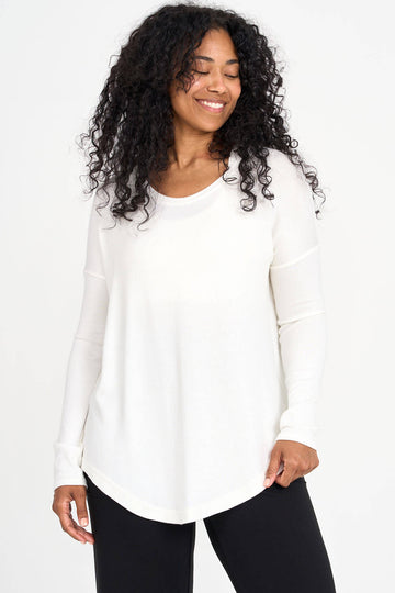 Woman wearing ivory Tencel scoopneck long sleeve top with split back hem, made by Canadian loungewear label Advika. 