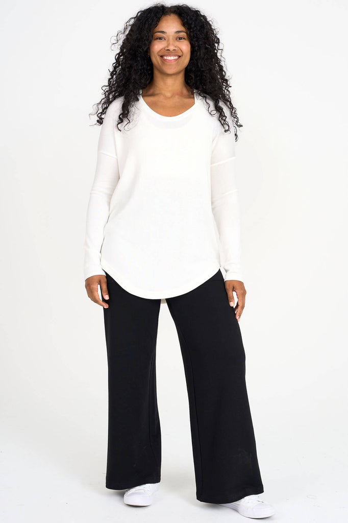 Woman wearing ivory Tencel scoopneck long sleeve top with split back hem, made by Canadian loungewear label Advika. 