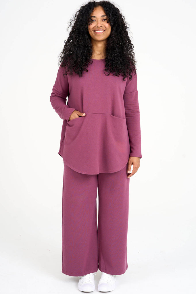 Woman wearing raspberry pink Tencel oversized long sleeve top with large front in-seam pockets and matching pants, made by Canadian loungewear label Advika. 