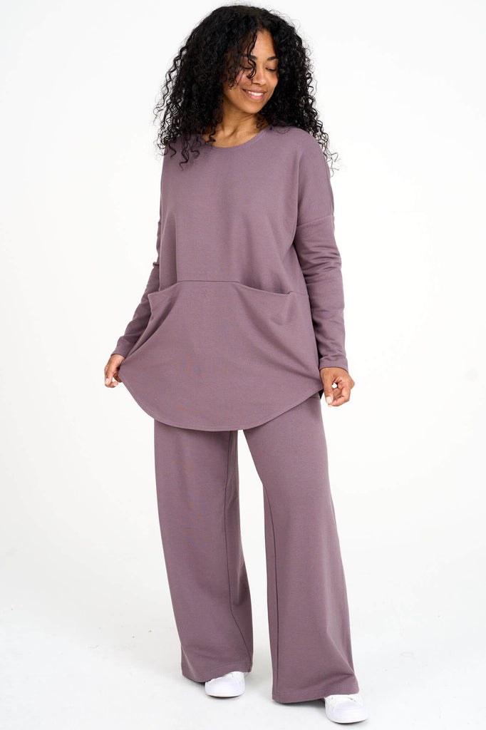 Woman wearing ube purple Tencel oversized long sleeve top with large front in-seam pockets and matching pants, made by Canadian loungewear label Advika. 