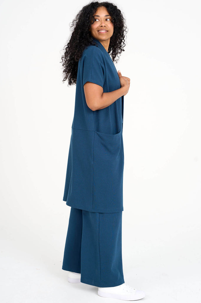 Side view of woman wearing bluebell blue tencel open front short sleeve duster cardigan and matching palazzo pants by Canadian loungewear designer Advika. 