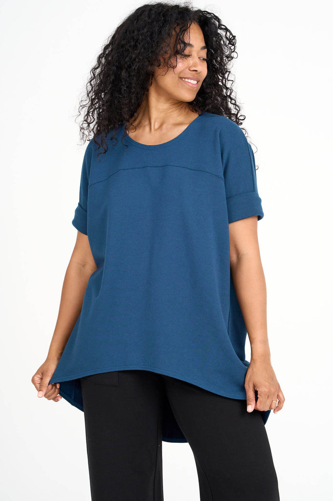 Woman wearing bluebell blue Tencel short sleeve slouchy top with back pleat detail, made by Canadian loungewear label Advika. 