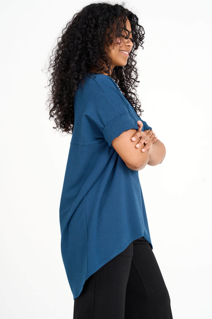 Side view of woman wearing bluebell blue Tencel short sleeve slouchy top with back pleat detail, made by Canadian loungewear label Advika. 
