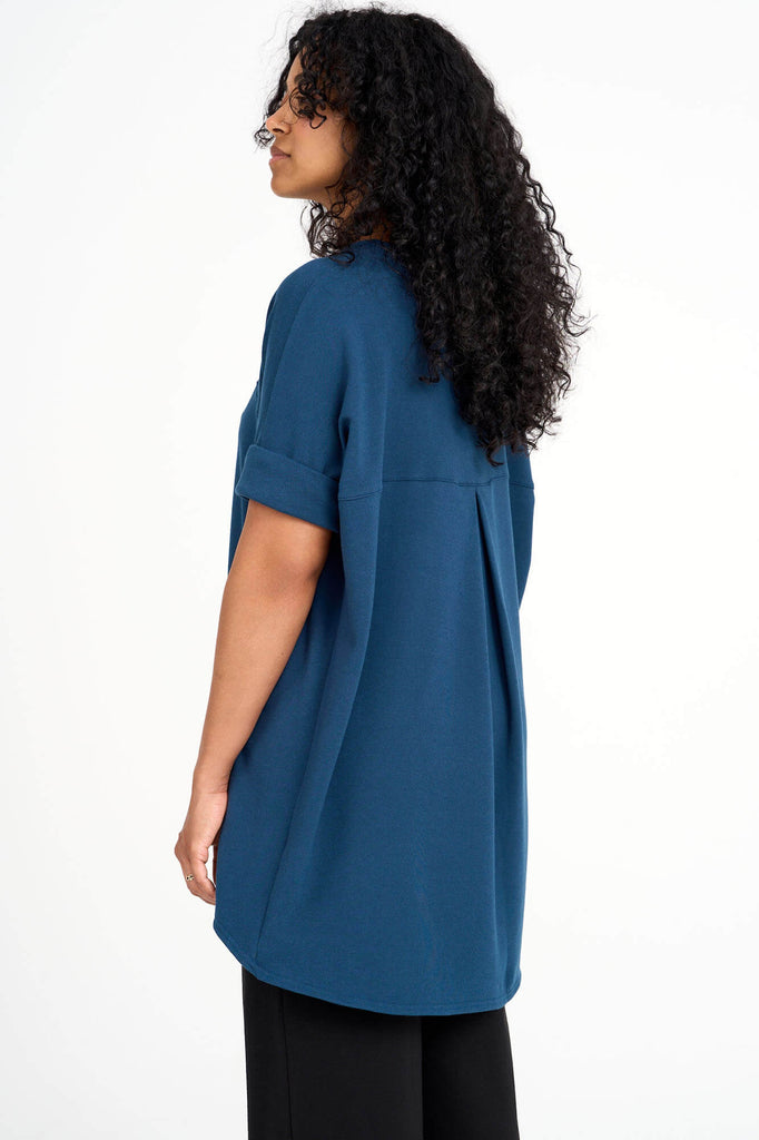 Back view of woman wearing bluebell blue Tencel short sleeve slouchy top with back pleat detail, made by Canadian loungewear label Advika. 