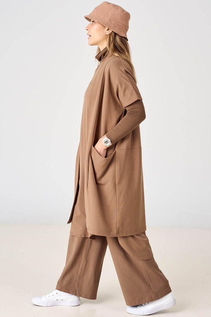 Woman wearing light brown long tencel open front cardigan layered over matching long sleeve top and wide leg pants by Advika. 