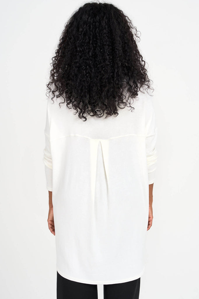 Back view of woman wearing ivory white Tencel long sleeve slouchy top with back pleat detail, made by Canadian loungewear label Advika. 