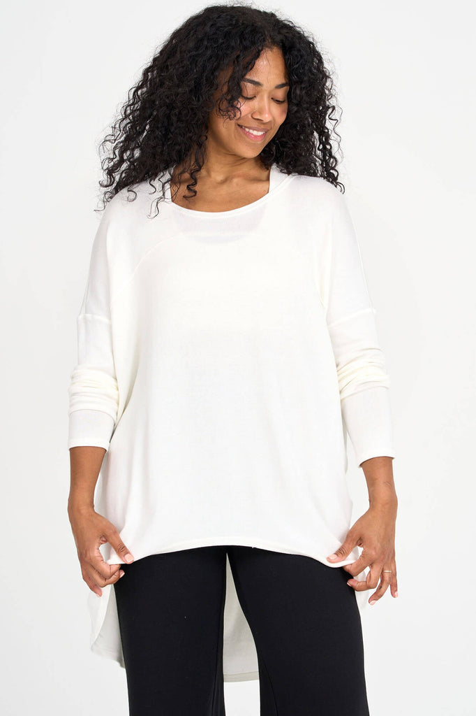 Woman wearing ivory white Tencel long sleeve slouchy top with back pleat detail, made by Canadian loungewear label Advika. 