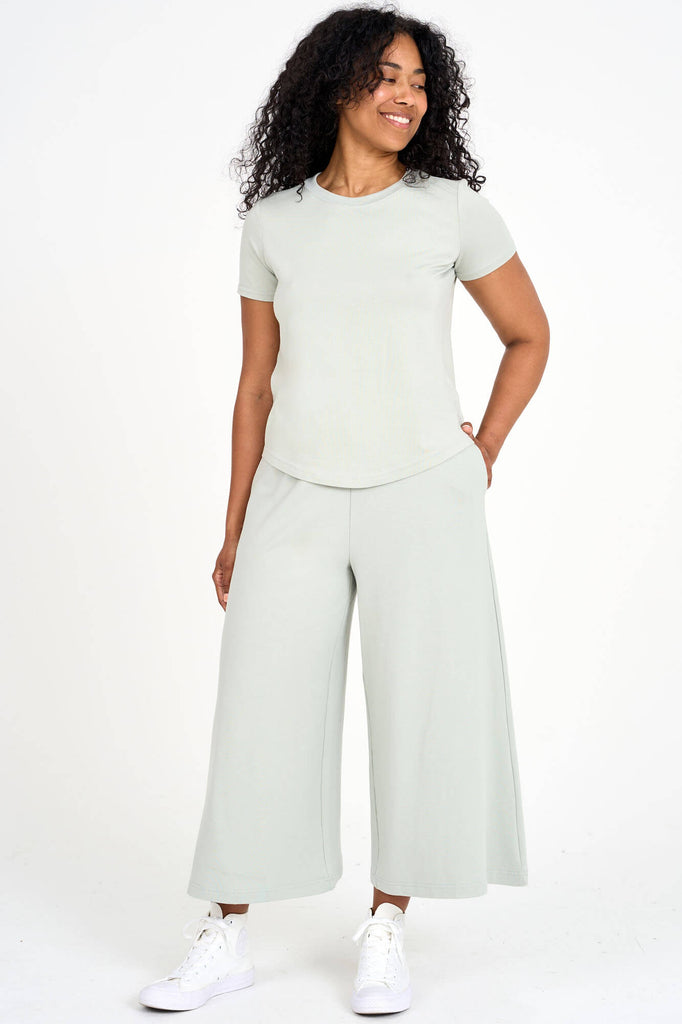Woman wearing light sage green Tencel blend wide leg gaucho pants with matching t-shirt, made by Canadian loungewear label Advika.