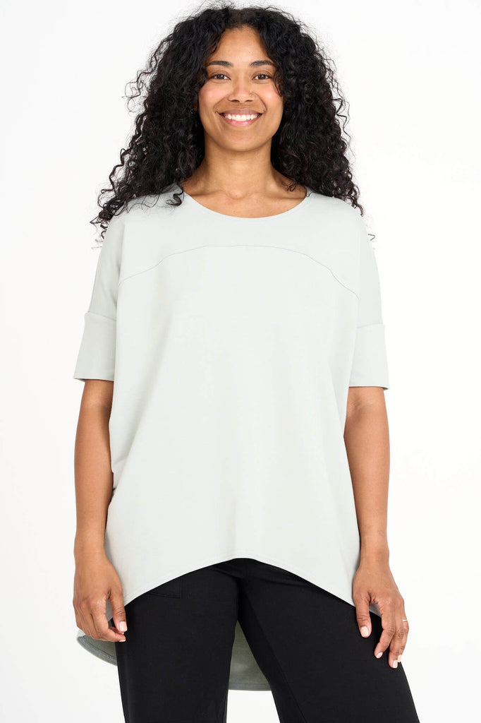 Woman wearing light sage green Tencel short sleeve slouchy top with back pleat detail, made by Canadian loungewear label Advika. 
