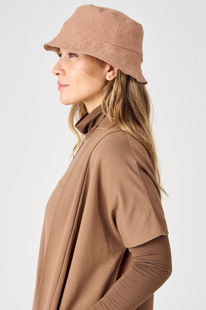 Woman wearing linen bucket hat in light brick colour. 
