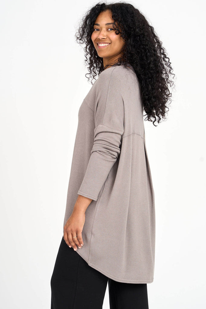 Side view of woman wearing mink beige Tencel long sleeve slouchy top with back pleat detail, made by Canadian loungewear label Advika. 