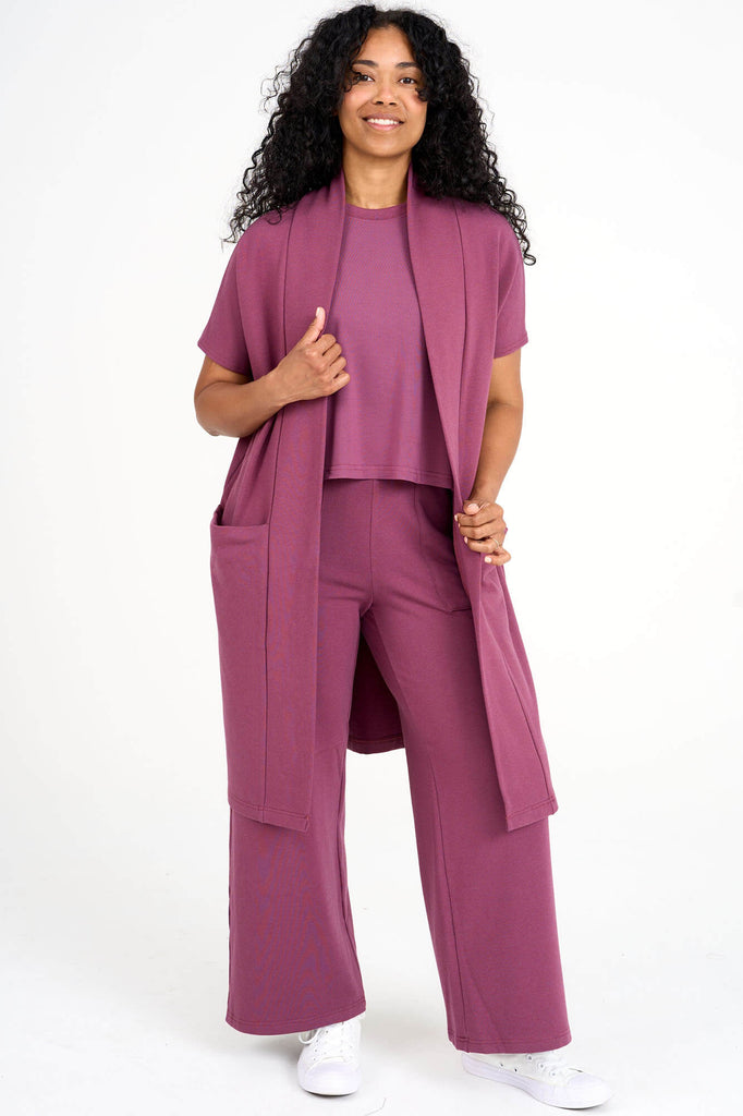 Woman wearing raspberry pink tencel open front short sleeve duster cardigan and matching palazzo pants by Canadian loungewear designer Advika. 
