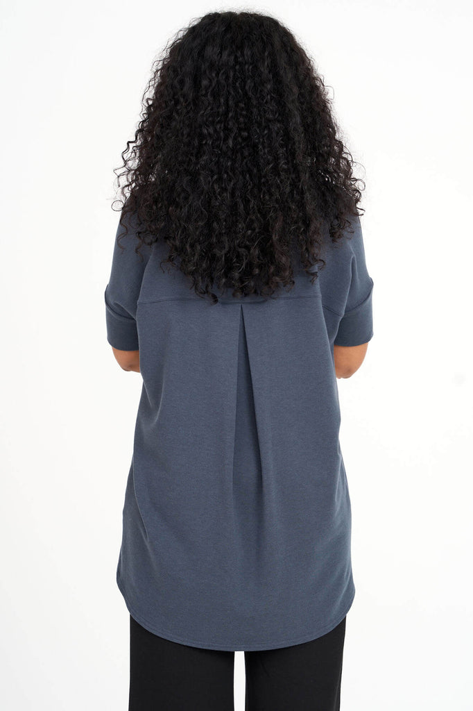 Back view of woman wearing steel blue Tencel short sleeve slouchy top with back pleat detail, made by Canadian loungewear label Advika. 