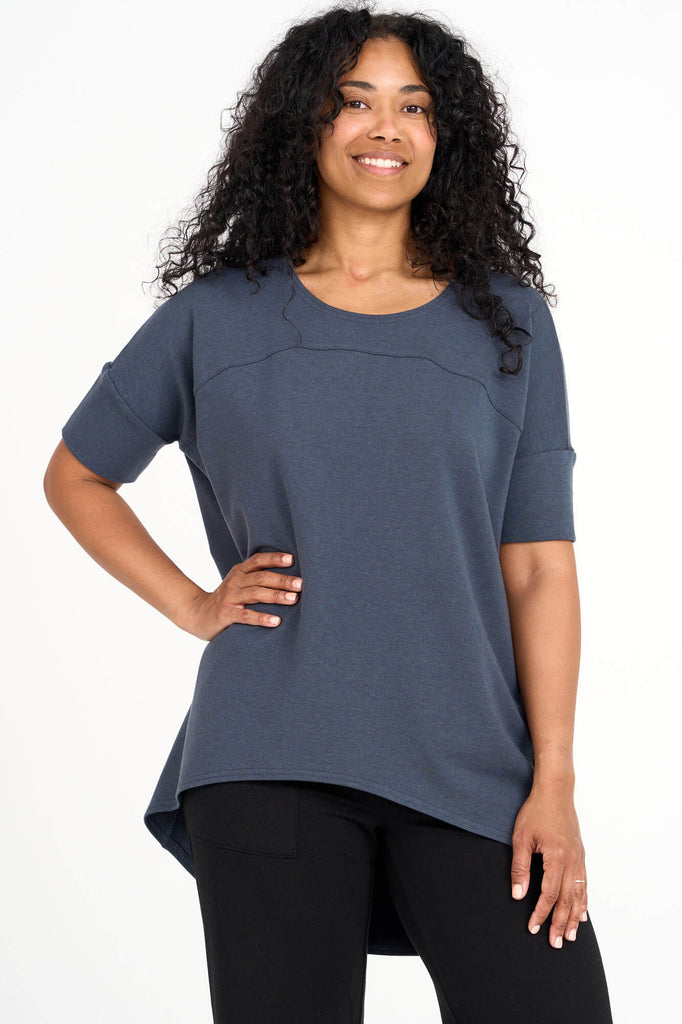 Woman wearing steel blue Tencel short sleeve slouchy top with back pleat detail, made by Canadian loungewear label Advika. 