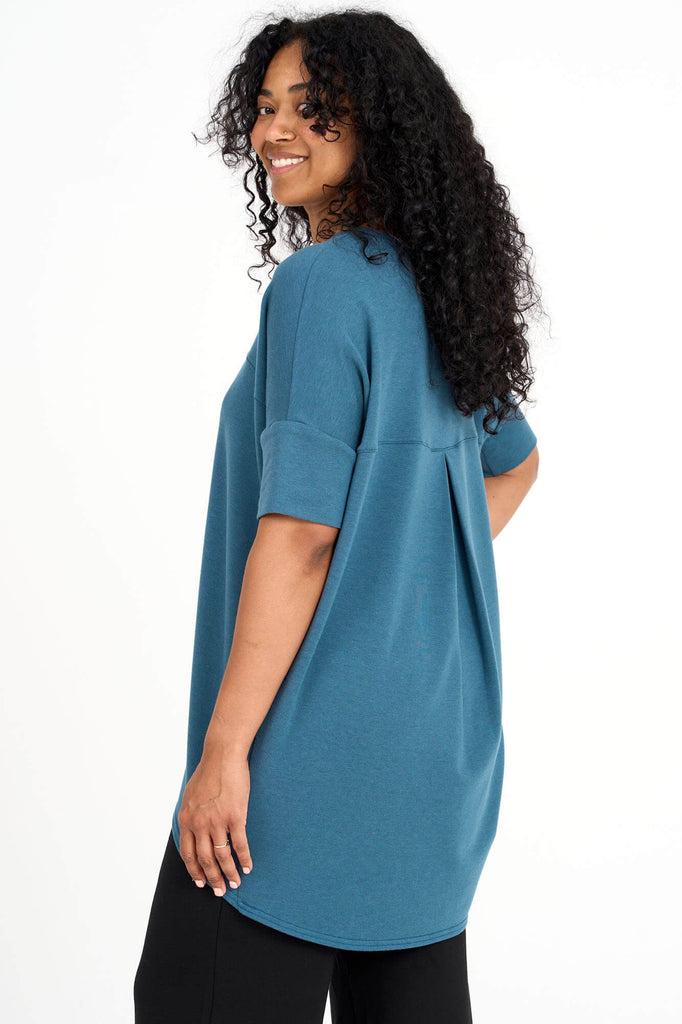Side view of woman wearing dusty teal short sleeve slouchy top with back pleat detail, made by Canadian loungewear label Advika. 