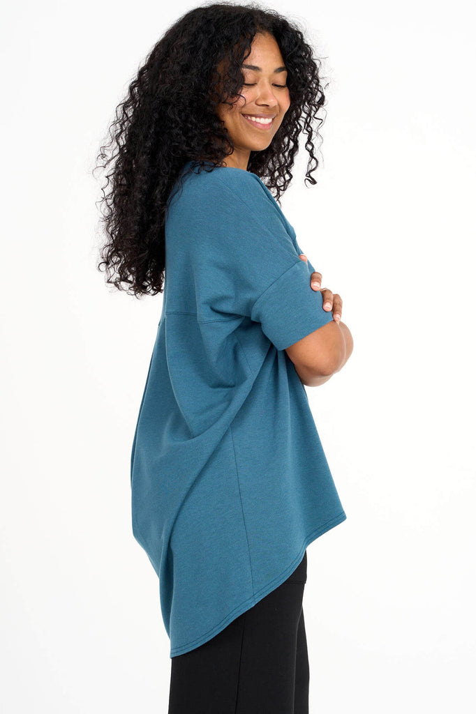 Side view of woman wearing dusty teal short sleeve slouchy top with back pleat detail, made by Canadian loungewear label Advika. 