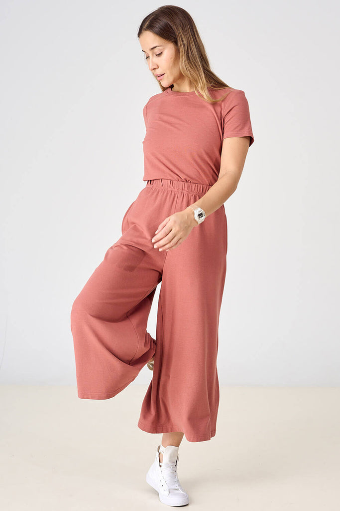 Woman wearing light brick pink Tencel blend wide leg gaucho pants with matching t-shirt, made by Canadian loungewear label Advika.