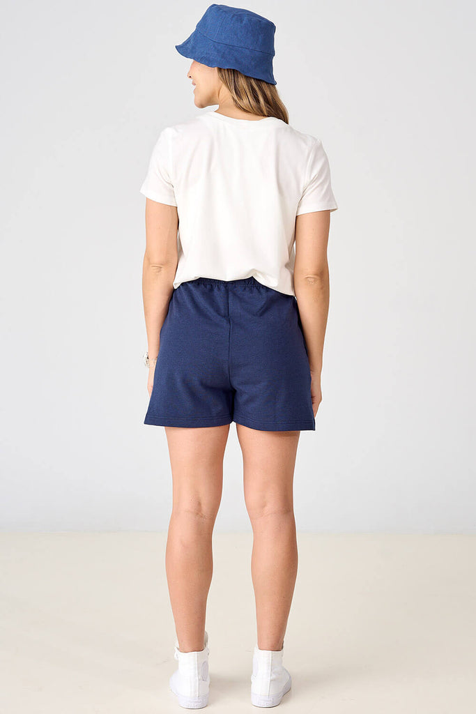 Woman wearing navy tencel shorts with white long sleeve top. 