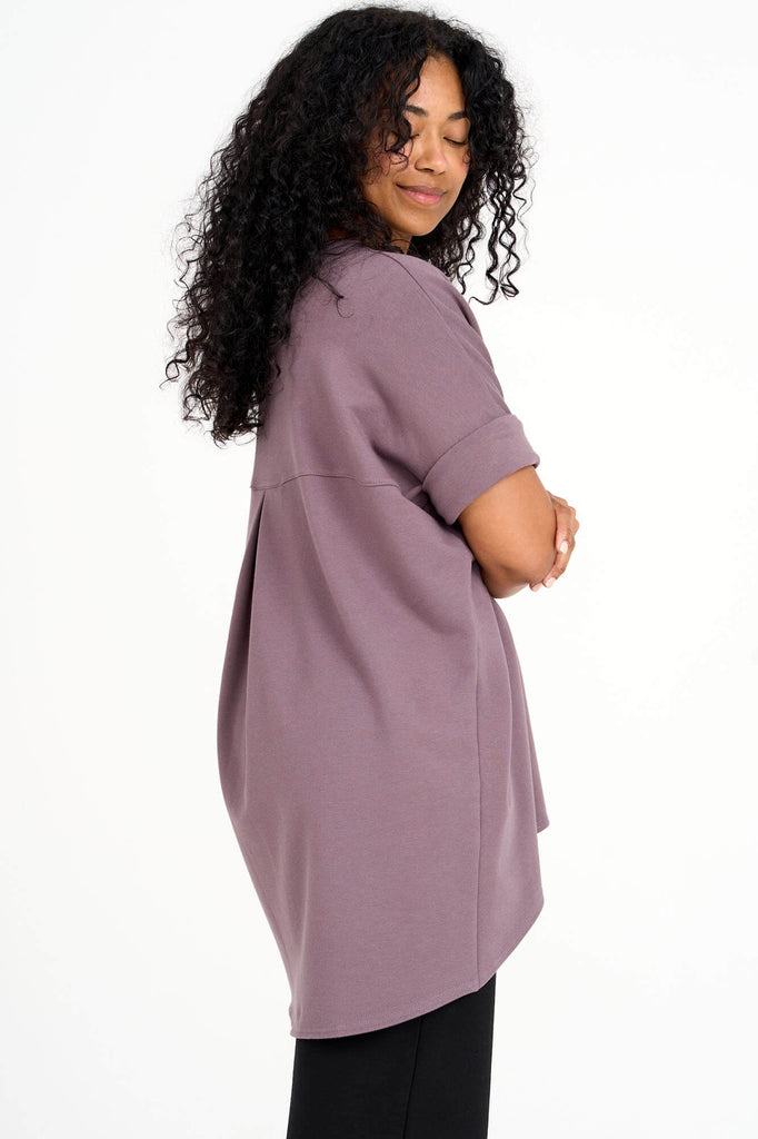 Side view of woman wearing ube purple Tencel short sleeve slouchy top with back pleat detail, made by Canadian loungewear label Advika. 