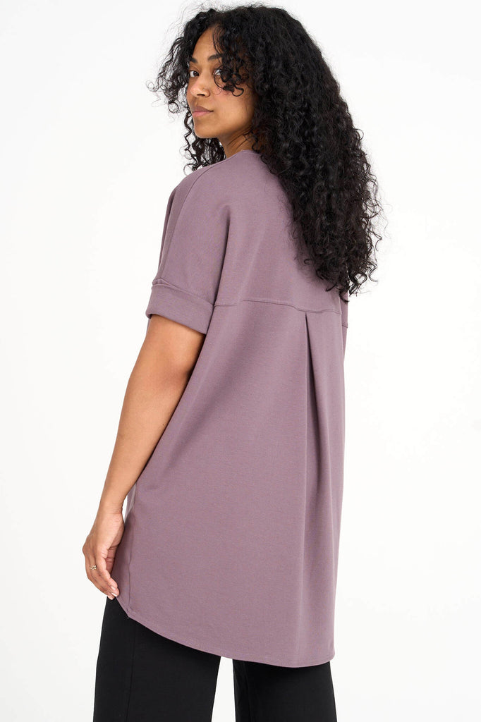 Back of woman wearing ube purple Tencel short sleeve slouchy top with back pleat detail, made by Canadian loungewear label Advika. 