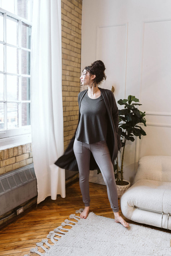 Woman wearing Tencel slim joggers in grey, Canadian made women's loungewear, standing by window