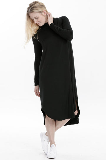 Woman wearing modal mock neck dress in black, Canadian made women's loungewear, legs crossed
